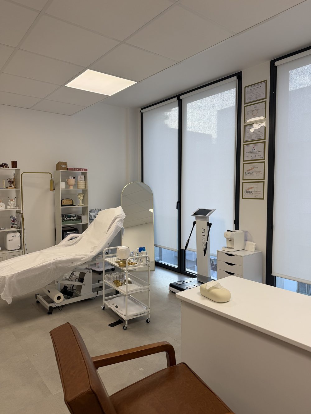 Une cabine de soins avec sa table de soin, ses appareils et les diplômes du médecin encadrés au mur